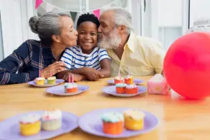 Older couple kissing grandson on the cheek at his birthday party
