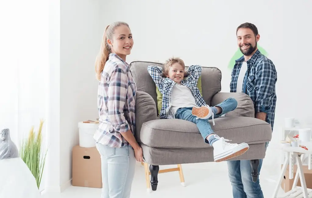 Young couple moving furniture with small child