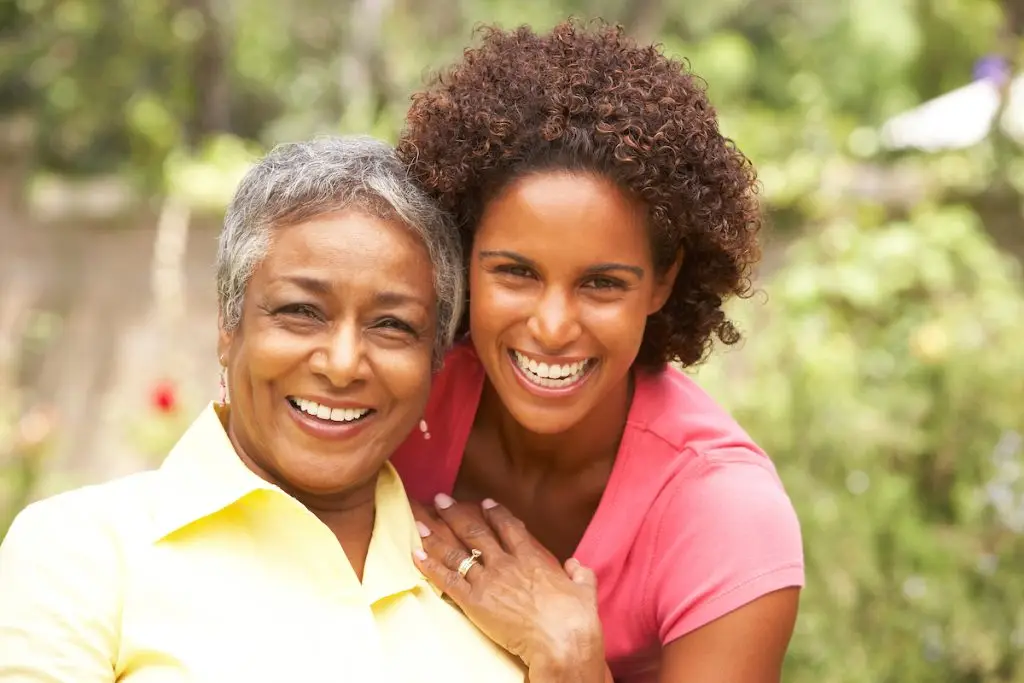 Senior Woman Hugging Adult Daughter In Garden