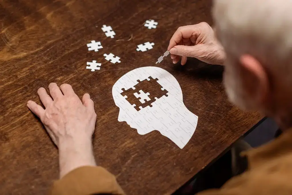 Senior man doing jigsaw puzzle of a human head with pieces missing