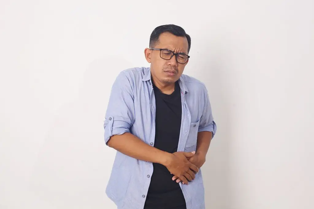 Man with diverticulitis holding left side of abdomen