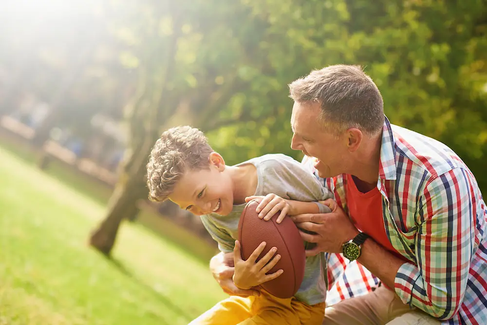 Father and son play football outdoors