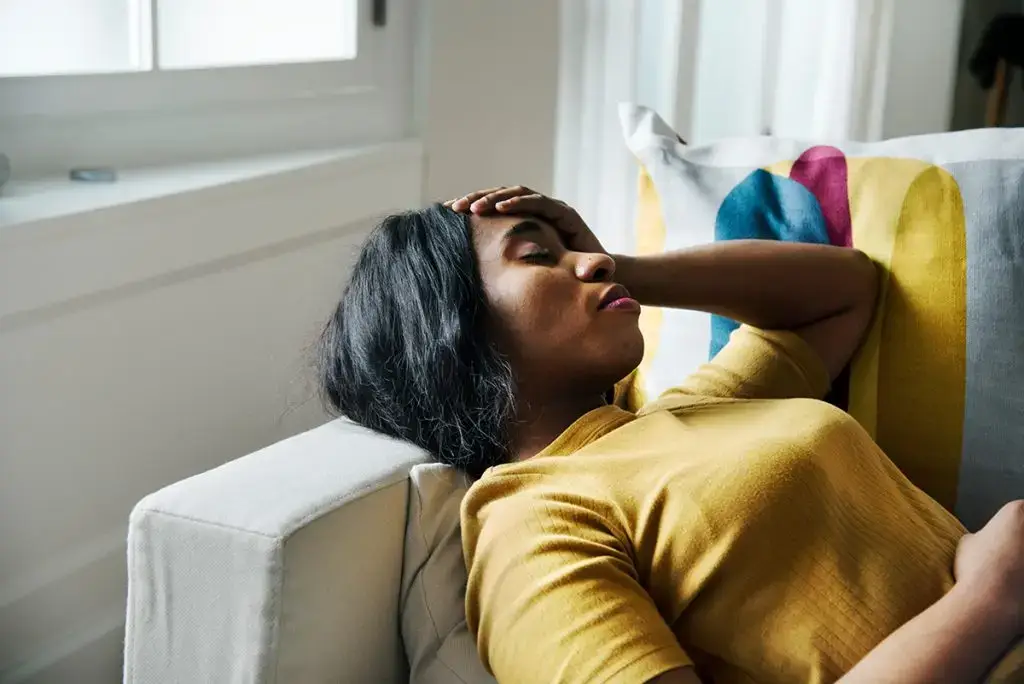 Woman laying on sofa with headache