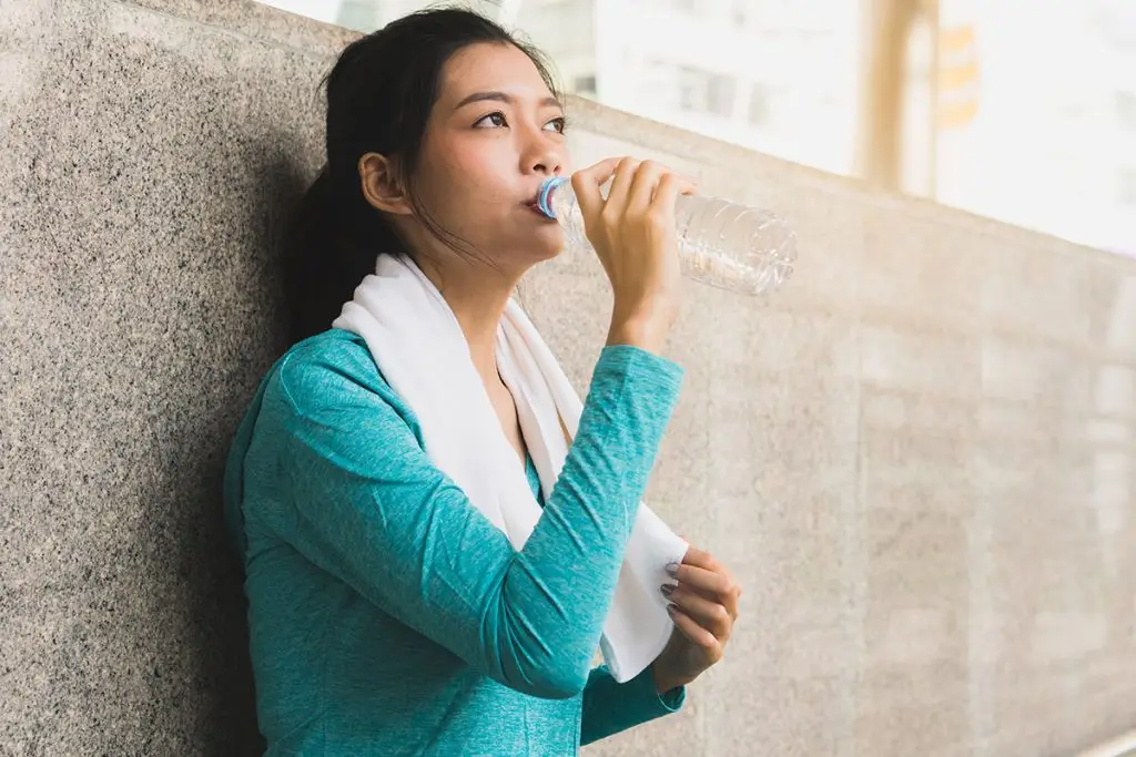 Woman drinking water after jogging