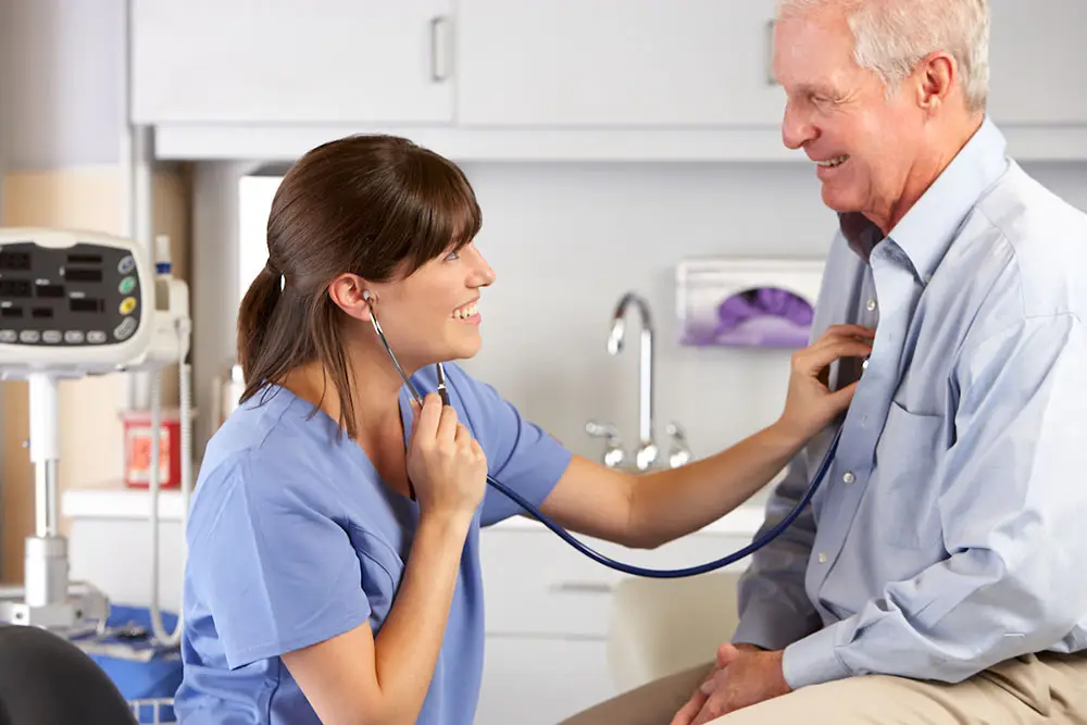 Provider listening to older patient's heart with stethoscope