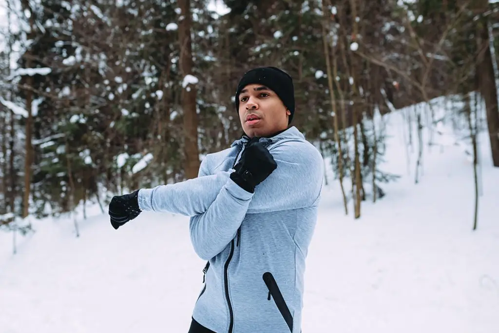 Man stretching outside on a snowy day