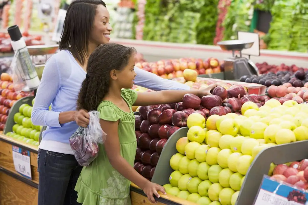 Mother and daughter picking apples out at grocery store