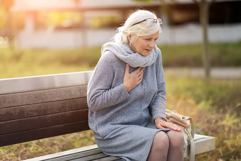 Older woman putting hand over chest as she experiences chest pain
