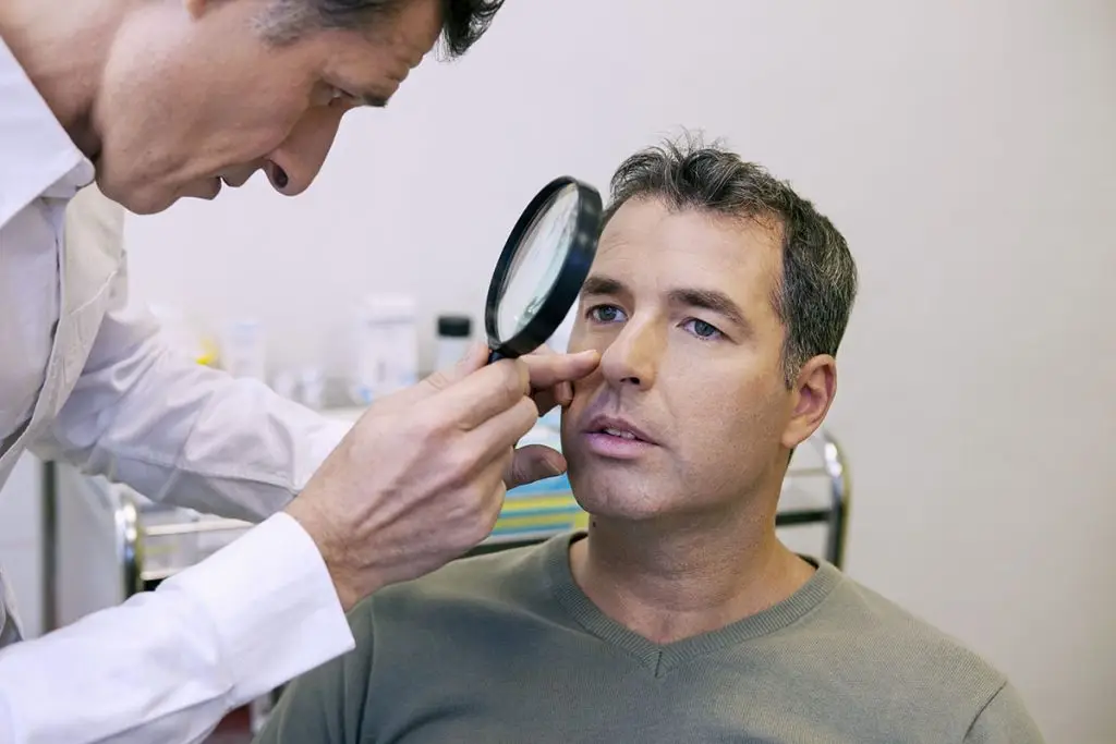 Doctor looking at man's face for skin cancer
