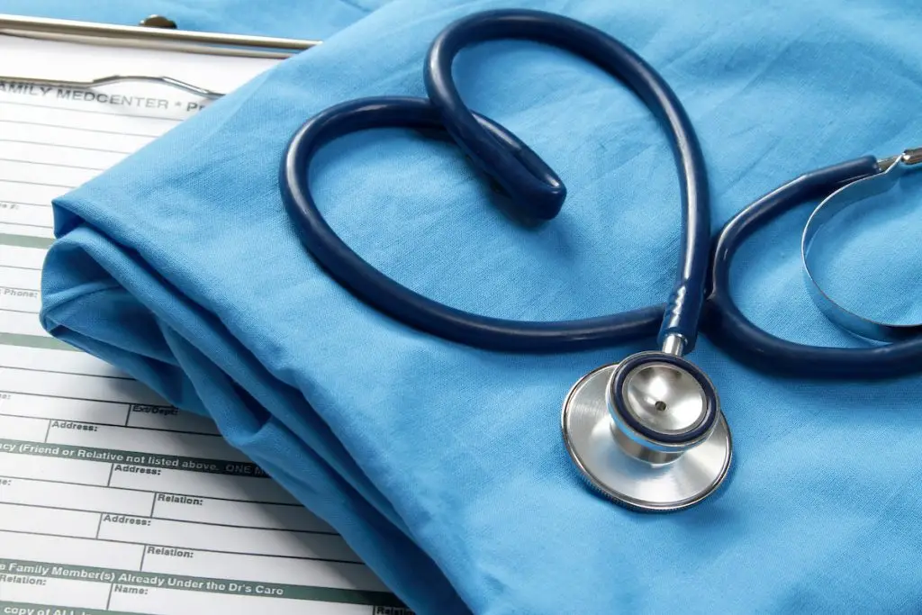 Stethoscope laid on folded scrubs in heart shape