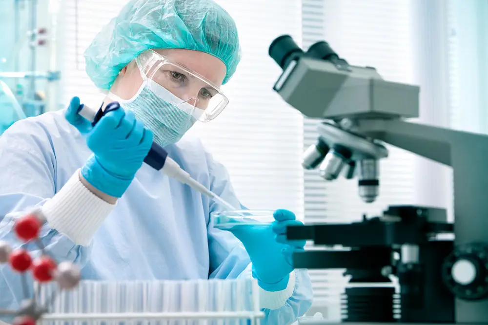 Woman with face mask working in a lab with a pipette