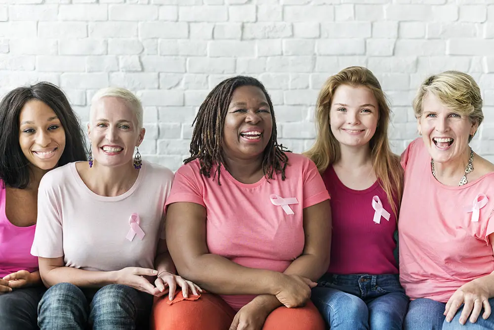 A diverse row of women of all ages and races wearing pink shirts for breast cancer