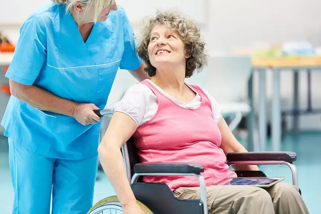 Woman in wheelchair being pushed by nurse