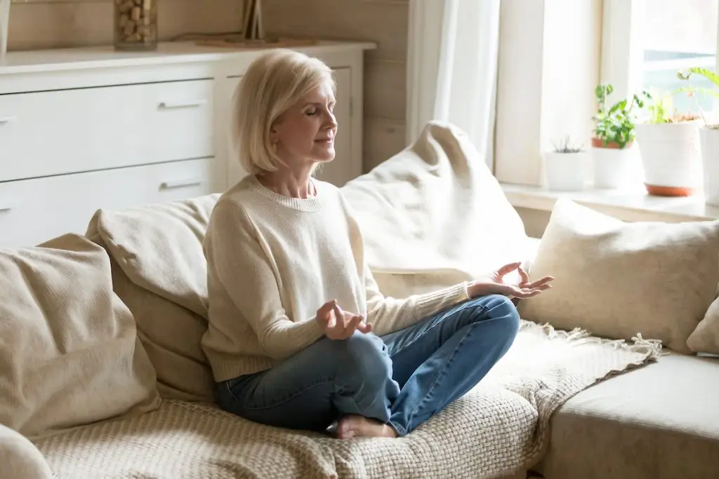 Older woman meditating on her sofa at home