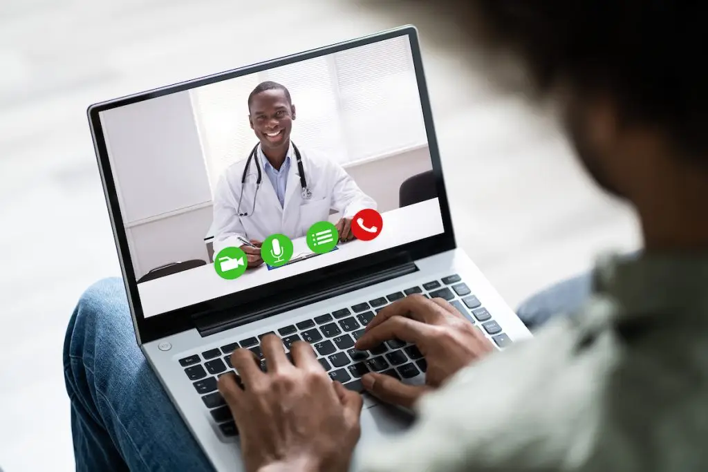 Man speaking to doctor on laptop for telemedicine appointment