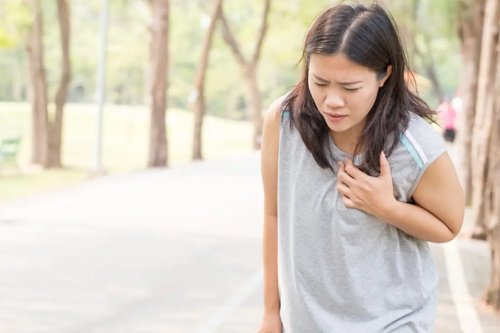 Young woman outside gripping her chest