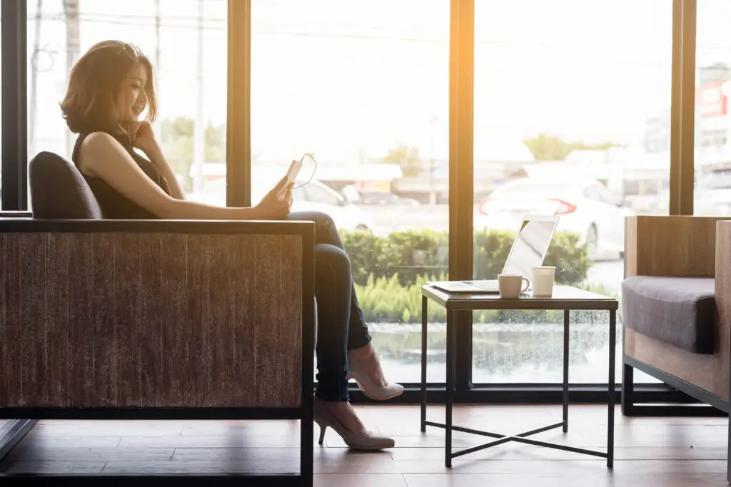 businesswomen sitting in front of window looking at phone